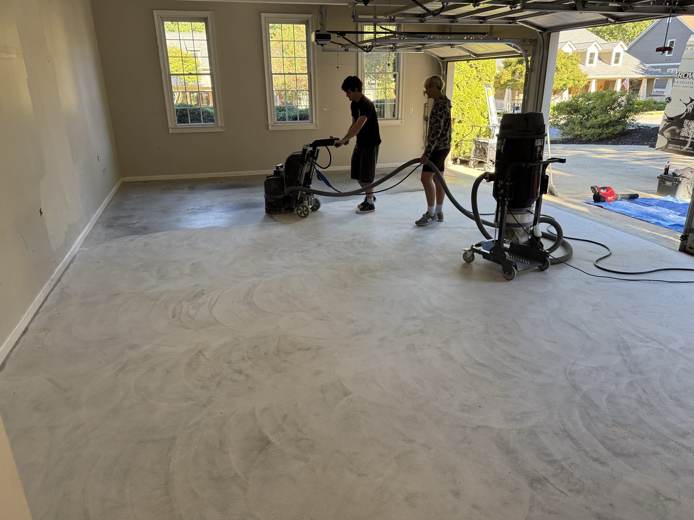 Homegrown Epoxy crew diamond grinding a garage floor with dust extraction